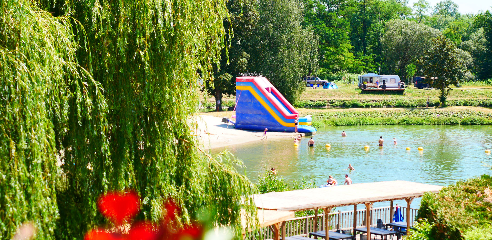 Baignade naturelle dans le plan d’eau équipé d’un toboggan et de jeux gonflables, du camping les Castors dans le Haut-Rhin