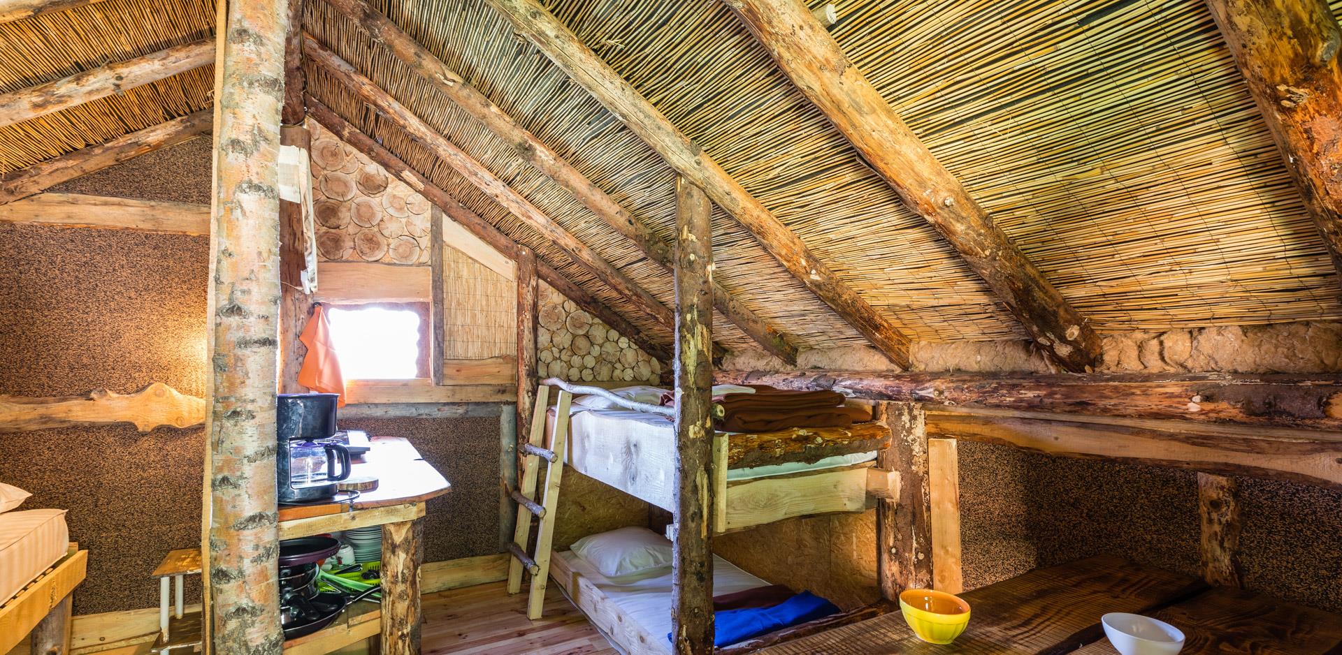 Vermietung von originellen Unterkünften im Oberelsass: Blick auf eine Kochecke und ein Hochbett in einer originellen Hütte.