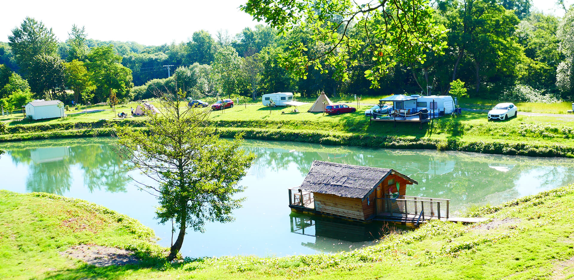 View of the natural swimming lake from the terrace of the atypical suspended hut Robin Hood, atypical accommodation at the Campsite Les Castors in Alsace.