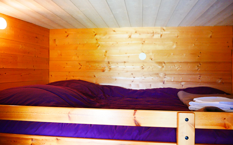 Bedroom with a double bed in the suspended in the trees hut Robin Hood, rental of atypical accommodations at the Campsite Les Castors near the Vosges Mountains